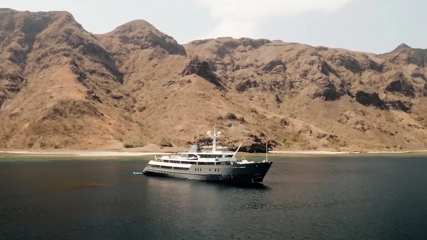 A yacht anchored beneath the sculpted hills of an Indonesian island