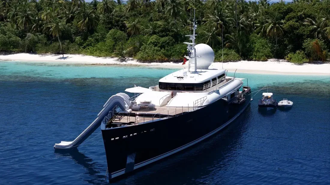 A contemporary motor yacht anchored beside a forested island